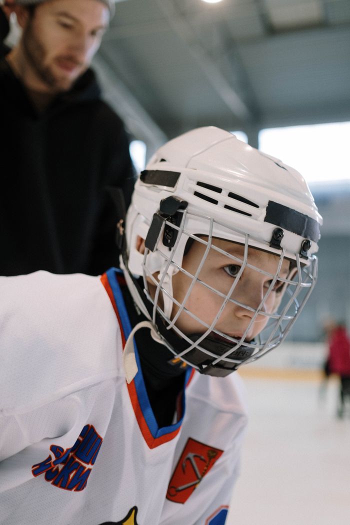 Focused young boy wearing full ice hockey gear during a practice session indoors.