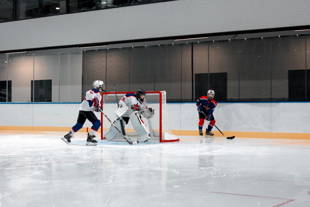 Action-packed ice hockey game with athletes, goalie, and dynamic play in an indoor arena.